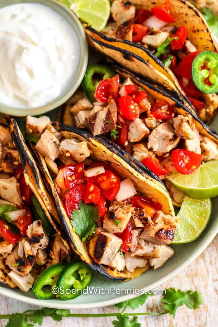 Street tacos on a plate with sour cream and limes