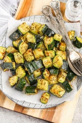 cooked Air fryer Zucchini on a plate with a fork and spoon