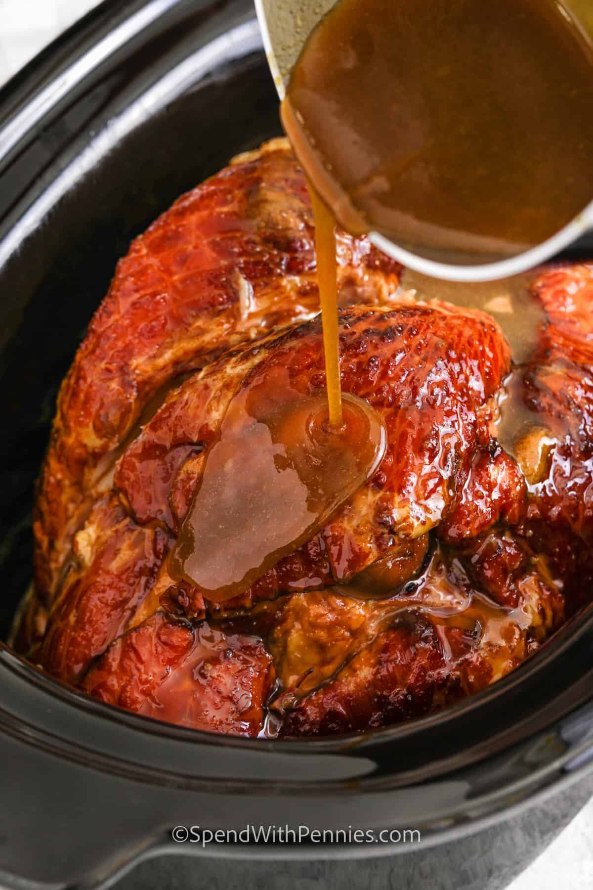 pouring glaze over ham to make Crock Pot Ham